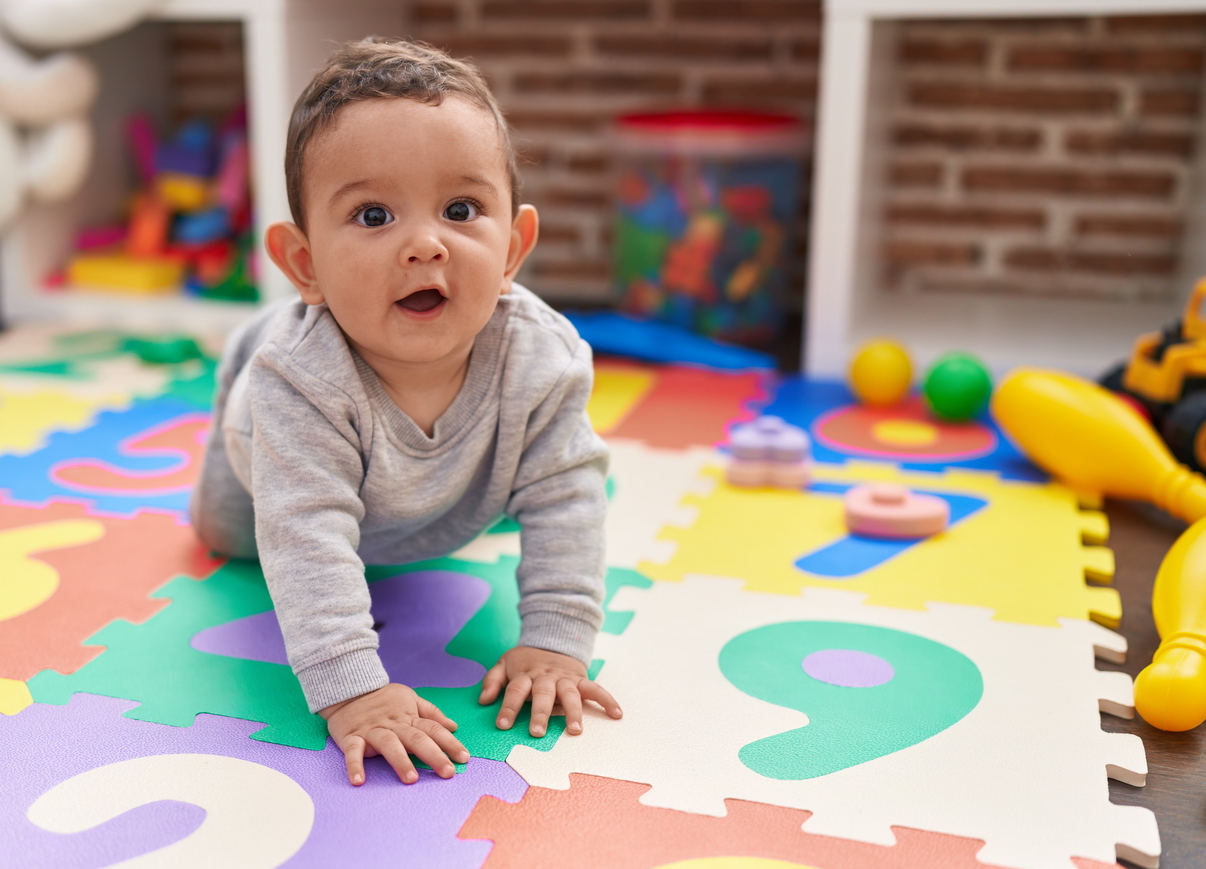 Adorable baby crawling on floor at kindergarten